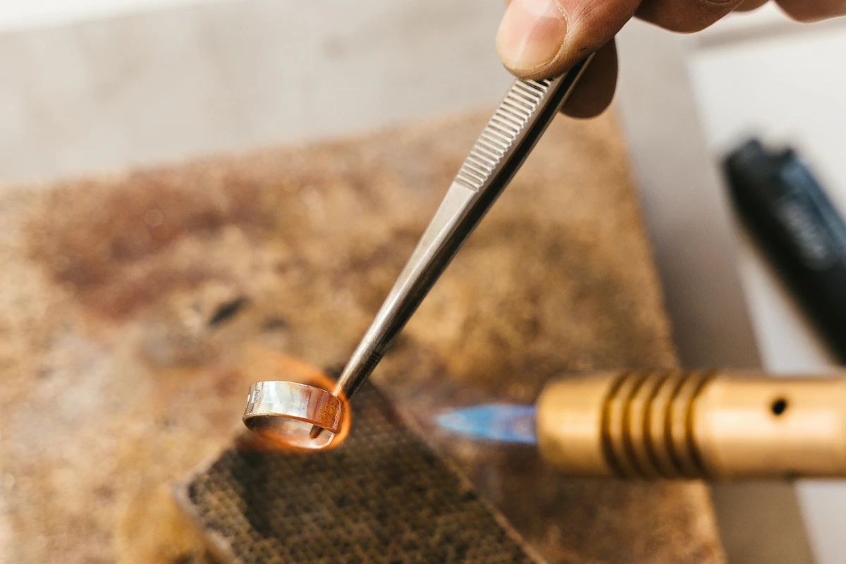 Jeweler making a gold ring, holding a  blowtorch to it 